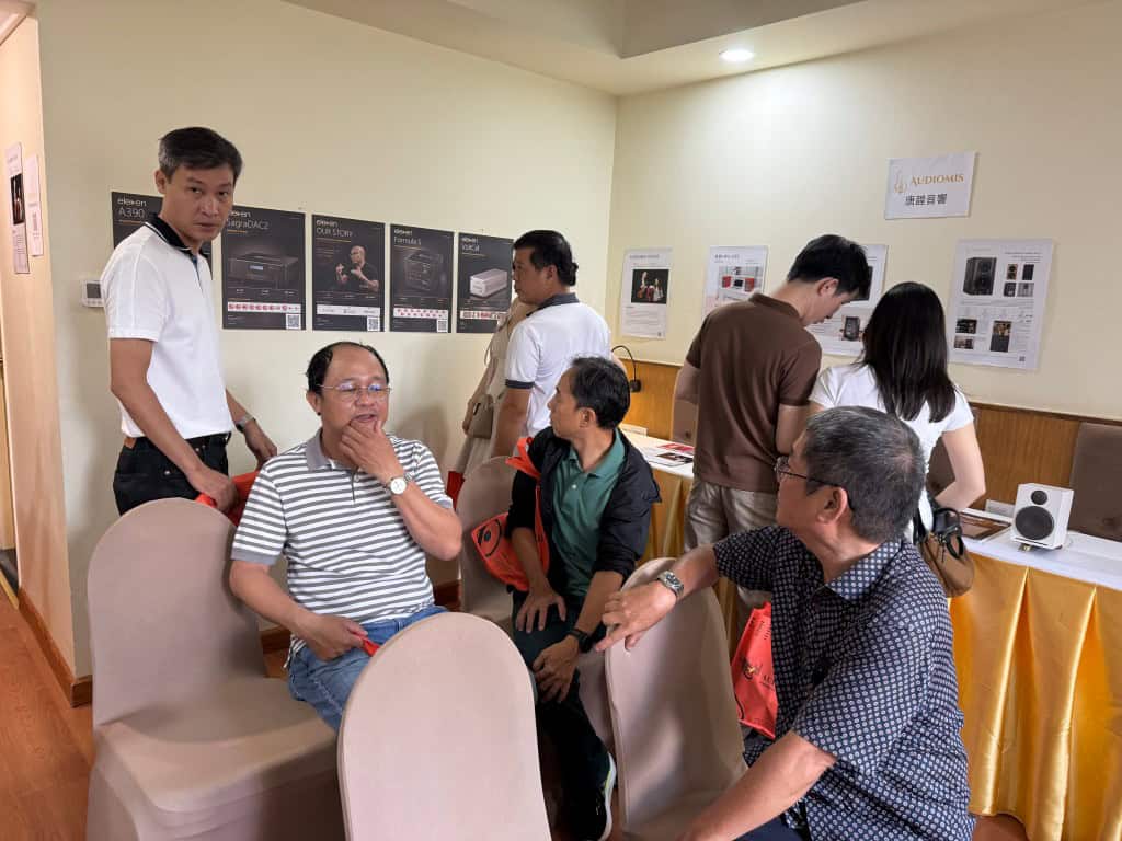 Group of people discussing high-end audio equipment at a showroom.