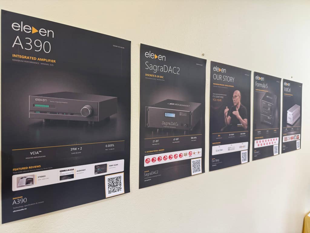 Display wall showcasing Eleven Audio high-end audio equipment and product posters.